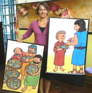 Photograph of a Pathway team member with posters illustrating the story of feeding the 5000
